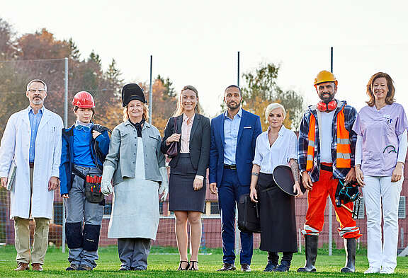 Acht Menschen in verschiedenen Berufsbekleidungen aus Unia-Branchen stehen nebeneinander.